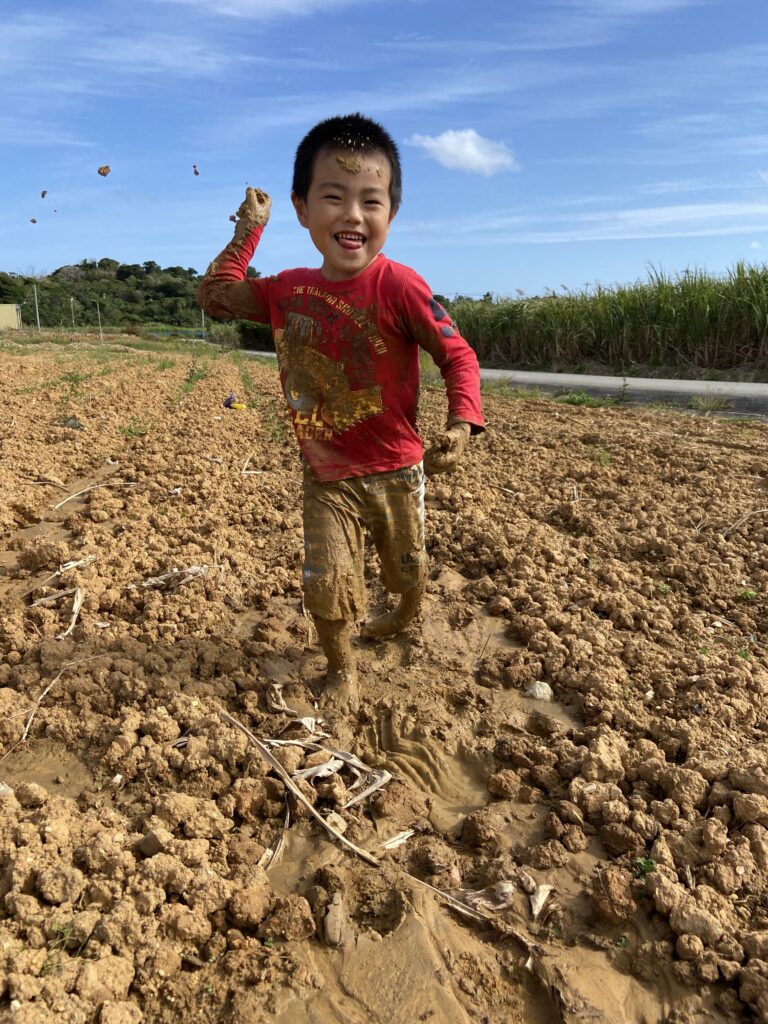 沖縄の畑で泥だらけになって笑う息子